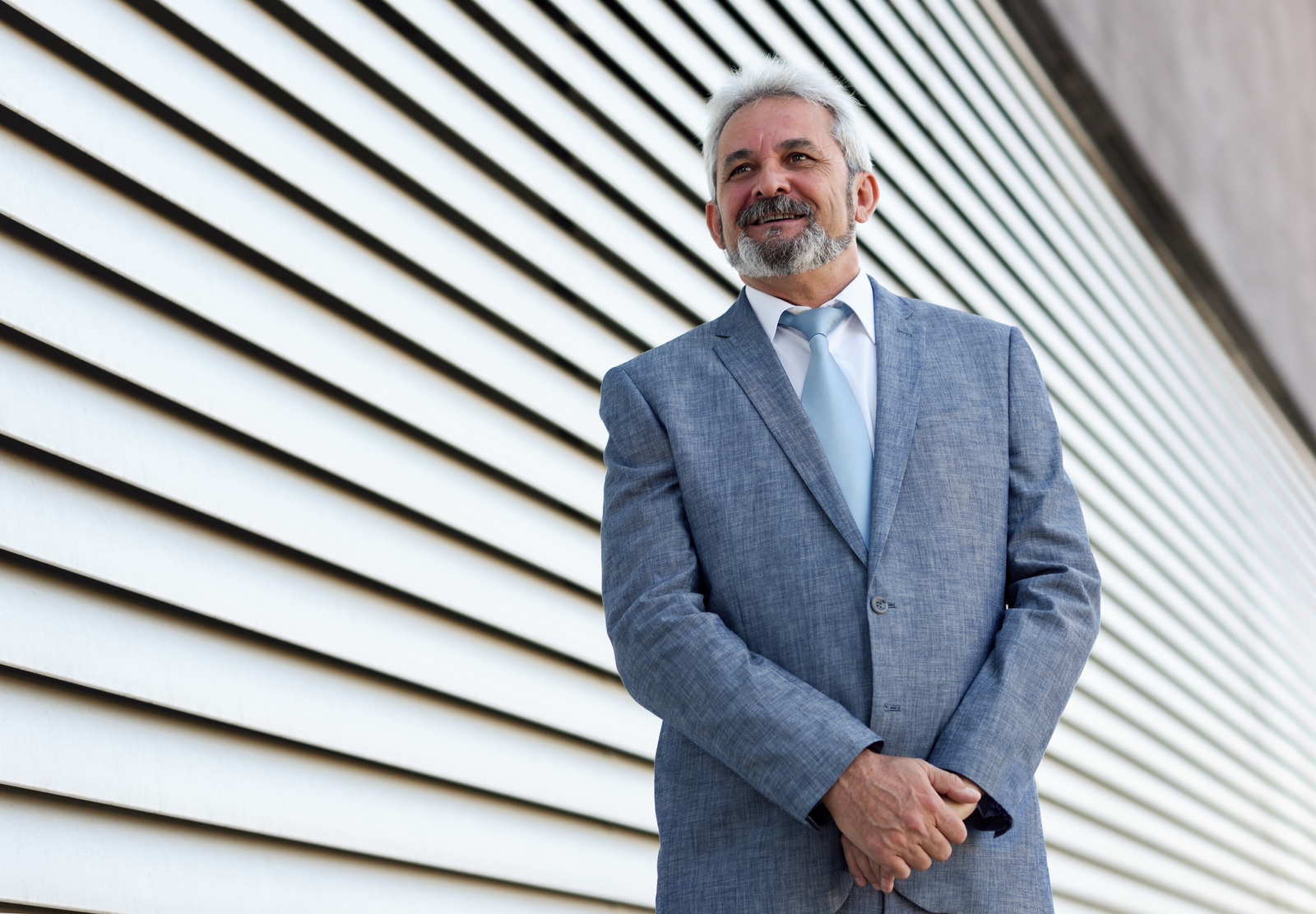 Senior businessman with arms crossed outside of modern office bu