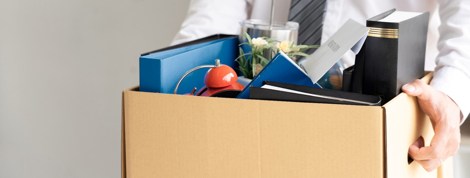 businessman has a brown cardboard box and resignation letter wri